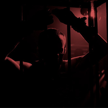 Homme tenant des barreaux d'une cage BDSM